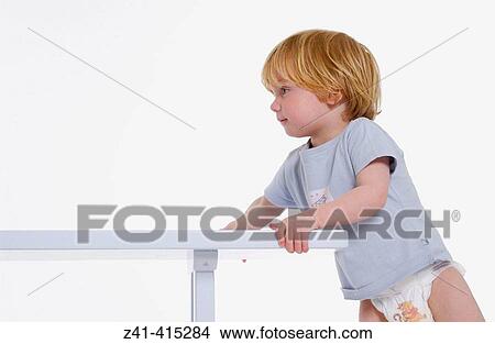 Toddler pushing against a bench View Large Photo Image Picture - Toddler pushing against a bench. Fotosearch