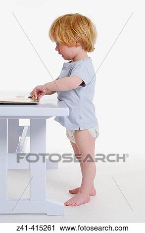 Stock Image - Toddler standing in front of a bench. Fotosearch