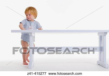 Toddler standing in front of a bench View Large Photo Image Stock Photo - Toddler standing in front of a bench. Fotosearch
