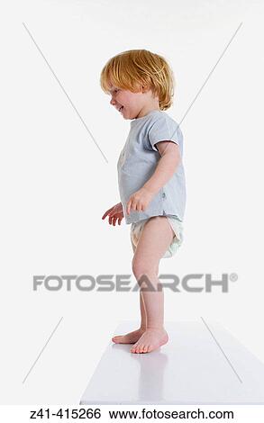 Stock Photograph - Toddler standing on of a bench. Fotosearch