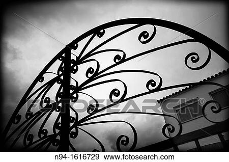 Stock Photo - Top of the iron gate wrought iron and the entrance to a home field.. Fotosearch