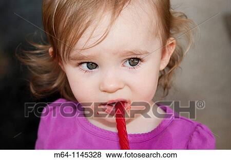 Tottler with big eyes eating red liquorice View Large Photo Image Stock Photo - Tottler with big eyes eating red liquorice. Fotosearch