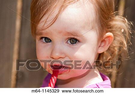 Stock Photo - Tottler with big eyes eating red liquorice. Fotosearch