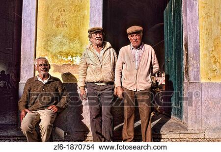 Picture - Tough and rough old fishermen relaxing at a bar in the village of Olmao in the Algarve in Southern Portugal in Europe. Fotosearch