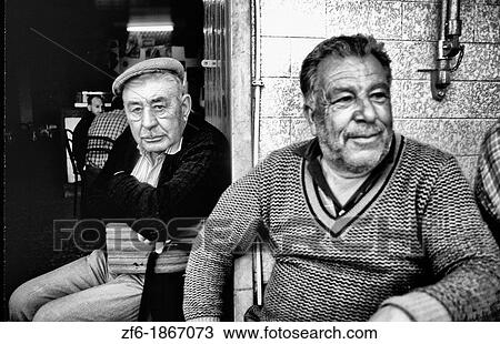 Stock Image - Tough and rough old fishermen relaxing at a bar in the village of Olmao in the Algarve in Southern Portugal in Europe.. Fotosearch