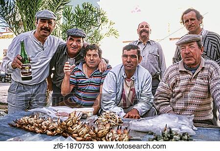 Stock Image - Tough and rough old fishermen relaxing at a bar in the village of Olmao in the Algarve in Southern Portugal in Europe. Fotosearch