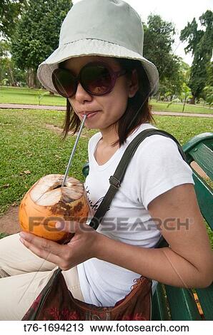 Stock Image - tourist enjoying a coconut in Colombo, Sri Lanka. Fotosearch