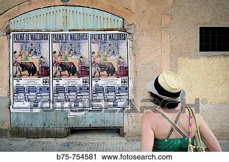 Stock Image - Tourist looking at bullfight posters. Majorca, Balearic Islands, Spain. Fotosearch
