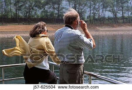 Picture - Tourist looking at mountains from boat on river, Guilin. China.. Fotosearch