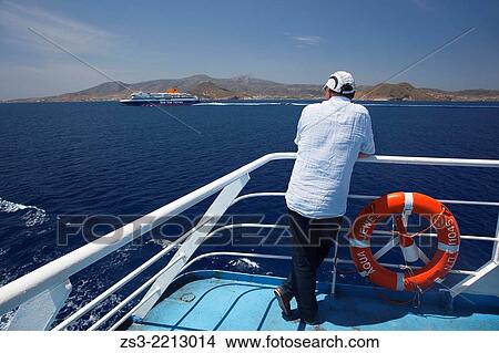Tourist looking from the ferry deck at the passing ferry, Naxos, Cyclades Islands, Greek Islands, Greece, Europe. View Large Photo Image Picture - Tourist looking from the ferry deck at the passing ferry, Naxos, Cyclades Islands, Greek Islands, Greece, Europe.. Fotosearch
