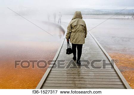 Tourist on boardwalk in steam over the fragile ground at the Grand Prismatic Spring, Midway Geyser Basin, Yellowstone National Park, Wyoming View Large Photo Image Stock Photo - Tourist on boardwalk in steam over the fragile ground at the Grand Prismatic Spring, Midway Geyser Basin, Yellowstone National Park, Wyoming. Fotosearch