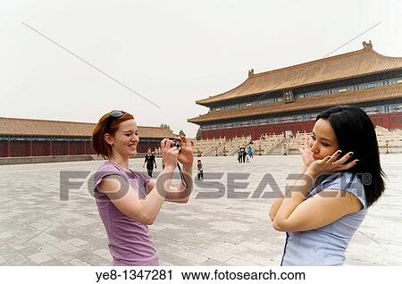 Stock Image - Tourist photographing her friend in front of the Hall for Worship Of Ancestors, The Forbidden City, Beijing, China, Asia MR. Fotosearch