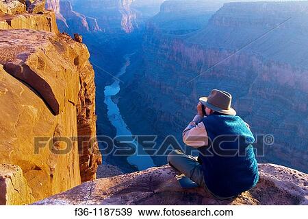 Tourist photographing the golden sunrise light on rock at the edge of a steep cliff above the Colorado River, Toroweap, Grand Canyon National Park, Arizona View Large Photo Image Stock Photo - Tourist photographing the golden sunrise light on rock at the edge of a steep cliff above the Colorado River, Toroweap, Grand Canyon National Park, Arizona. Fotosearch