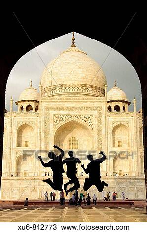 Stock Image - Tourist teens jumping in front of the Taj Mahal Agra, India. Fotosearch
