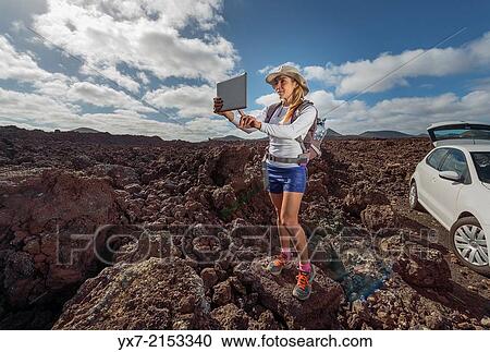 Stock Image - Tourist using a Tablet at Timanfaya National Park, Lanzarote, Canary Islands, Spain.. Fotosearch