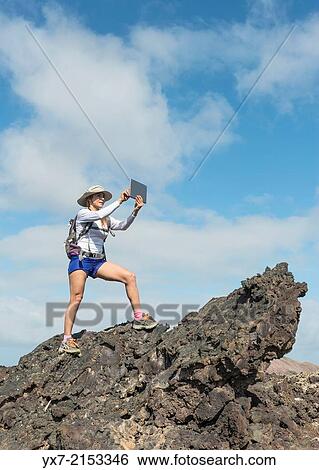Stock Photograph - Tourist using a Tablet at Timanfaya National Park, Lanzarote, Canary Islands, Spain.. Fotosearch