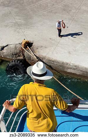 Tourist with straw hat looking from the ferry deck at the pier staff with rope, Milos, Cyclades Islands, Greek Islands, Greece, Europe. View Large Photo Image Stock Photography - Tourist with straw hat looking from the ferry deck at the pier staff with rope, Milos, Cyclades Islands, Greek Islands, Greece, Europe.. Fotosearch