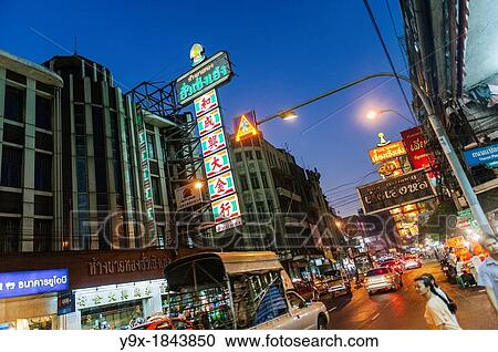 Stock Image - Tourists and locals eating at street vendors and visiting shops in a busy Thailand City. Fotosearch