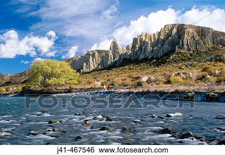 Tourists beneath Clay Cliffs. Autumn colours. Near Omarama. New Zealand. View Large Photo Image Stock Photograph - Tourists beneath Clay Cliffs. Autumn colours. Near Omarama. New Zealand.. Fotosearch