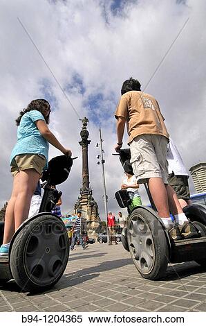 Tourists on Segway (Two-wheeled electric vehicle, invented by Dean Kamen and introduced the year 2001) and Colon monument, Barcelona, Catalonia, Spain View Large Photo Image Stock Photography - Tourists on Segway (Two-wheeled electric vehicle, invented by Dean Kamen and introduced the year 2001) and Colon monument, Barcelona, Catalonia, Spain. Fotosearch