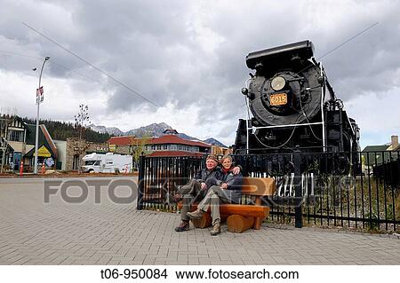 Picture - Tourists sitting in front of the historic steam locomotive, town of Jasper, Jasper National Park, Rocky Mountains, Alberta, Canada. Fotosearch