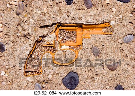 Picture - Toy gun encrusted in cement. Fotosearch