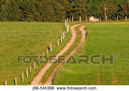 Stock Photo - Track with fence and meadow. Bavaria, Germany, Europe.. Fotosearch