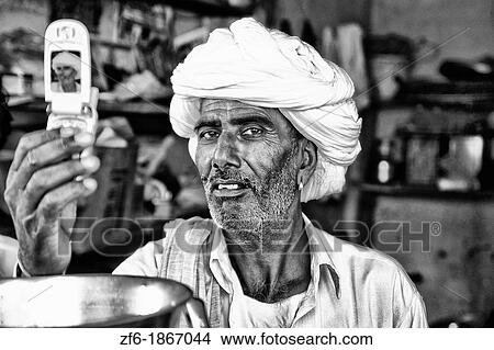 Traditional Hindu vendor man with white turban portrait using modern technology cell phone camera to take picture in Jaipur Rajasthan India View Large Photo Image Picture - Traditional Hindu vendor man with white turban portrait using modern technology cell phone camera to take picture in Jaipur Rajasthan India. Fotosearch