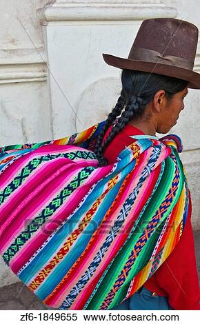 Stock Photography - Traditional woman in costume and back pack in Cuzco Cusco Peru. Fotosearch