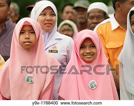 Stock Image - Traditionally dressed women and children standing and smiling during a rally in Malaysia. Fotosearch