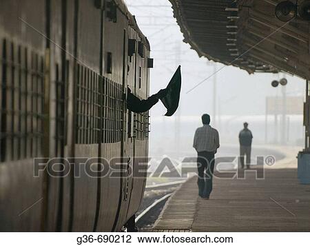 Train conductor waves flag as a signal as he leaves station in Bangalore, India View Large Photo Image Stock Image - Train conductor waves flag as a signal as he leaves station in Bangalore, India. Fotosearch