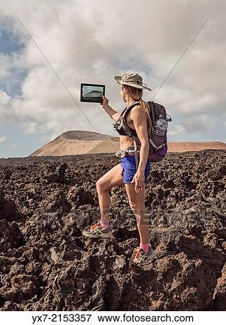 Traveler using a tablet at Timanfaya National Park, Lanzarote, Canary Islands, Spain. View Large Photo Image Stock Photo - Traveler using a tablet at Timanfaya National Park, Lanzarote, Canary Islands, Spain.. Fotosearch