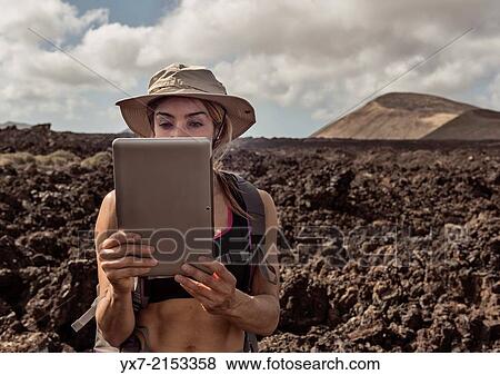 Traveler using a tablet at Timanfaya National Park, Lanzarote, Canary Islands, Spain. View Large Photo Image Stock Photo - Traveler using a tablet at Timanfaya National Park, Lanzarote, Canary Islands, Spain.. Fotosearch