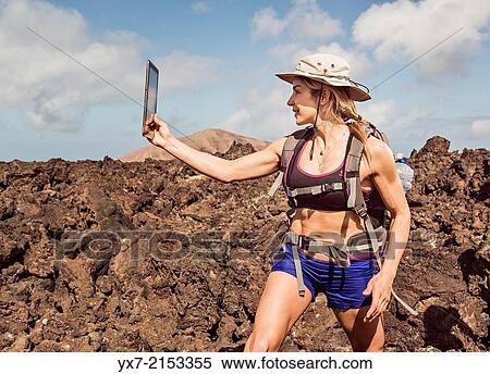 Stock Photography - Traveler using a tablet at Timanfaya National Park, Lanzarote, Canary Islands, Spain.. Fotosearch