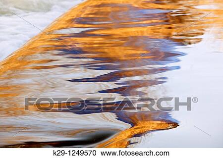 Stock Image - Tree reflections in flowing water of Junction Creek in winter. Fotosearch
