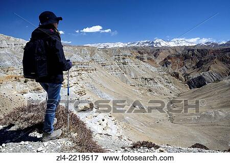 Trekker and mineral landscape between Lo Manthang and the village of Dhie Gaon. Nepal, Gandaki, Upper Mustang (near the border with Tibet). Model Released. View Large Photo Image Stock Photo - Trekker and mineral landscape between Lo Manthang and the village of Dhie Gaon. Nepal, Gandaki, Upper Mustang (near the border with Tibet). Model Released.. Fotosearch