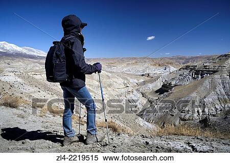 Stock Photography - Trekker and mineral landscape between Lo Manthang and the village of Dhie Gaon. Nepal, Gandaki, Upper Mustang (near the border with Tibet). Model Released.. Fotosearch