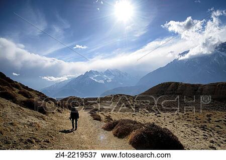 Stock Photo - Trekker and mountains between the villages of Tangge and Chuksang. Nepal, Gandaki, Upper Mustang (near the border with Tibet). Model Released.. Fotosearch