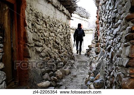 Trekker in a narrow lane of Tangbe village. Nepal, Gandaki, Upper Mustang (near the border with Tibet). Model Released. View Large Photo Image Picture - Trekker in a narrow lane of Tangbe village. Nepal, Gandaki, Upper Mustang (near the border with Tibet). Model Released.. Fotosearch