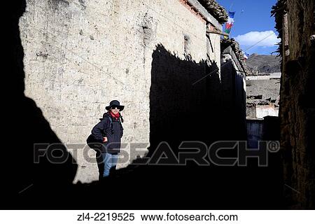 Stock Photography - Trekker in a street of the village of Tangge. Nepal, Gandaki, Upper Mustang (near the border with Tibet). Model Released.. Fotosearch