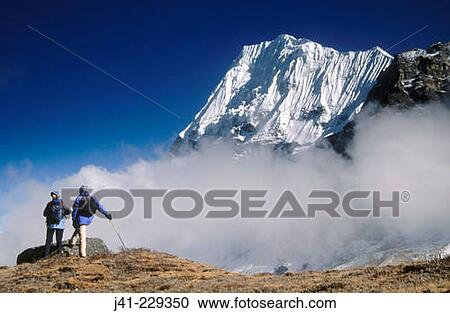 Stock Image - Trekkers. Wedge Peak above cloud. Lhonak. Kangchenjunga. East Nepal. Fotosearch