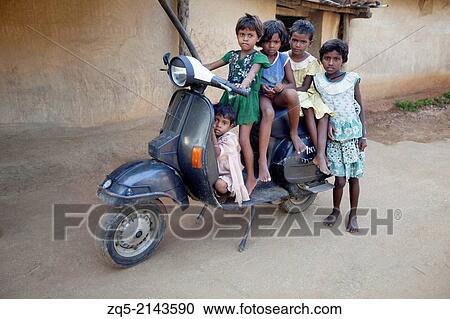 Stock Image - Tribal children sitting on a scooter. Santhal tribe. Jarkatand village, Bokaro district, Jharkhand.. Fotosearch