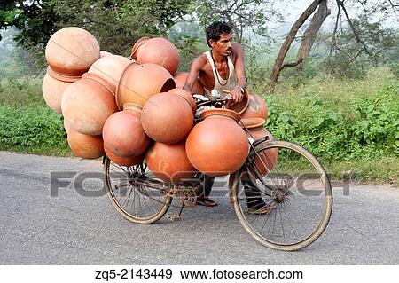 Tribal man carrying pots to the market on a bicycle. Kurmali tribe. Bokaro District Jharkhand, India. View Large Photo Image Stock Photo - Tribal man carrying pots to the market on a bicycle. Kurmali tribe. Bokaro District Jharkhand, India.. Fotosearch