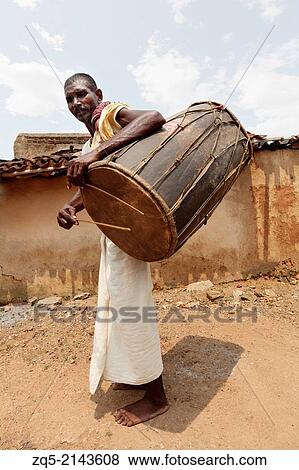 Stock Photo - Tribal musician playing a traditional musical instrument known as dholak. Uraov tribe. Baludih village, Bokaro district, Jharkhand.. Fotosearch