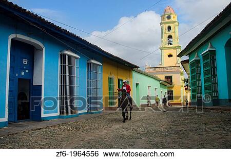Trinidad Cuba old cobblestone street with cowboy on horse walking his bird outdoors and beautiful church in city. View Large Photo Image Stock Photograph - Trinidad Cuba old cobblestone street with cowboy on horse walking his bird outdoors and beautiful church in city.. Fotosearch