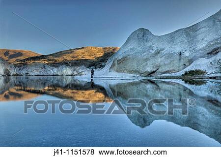 Stock Photo - Trout fisherman, Blue lake reflection, dawn, St Bathan? s, Central Otago. Fotosearch