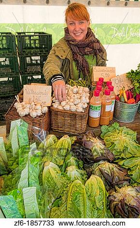 Stock Image - Turku Finland woman selling vegetables center city Main Town Square Kauppatori sunshine. Fotosearch