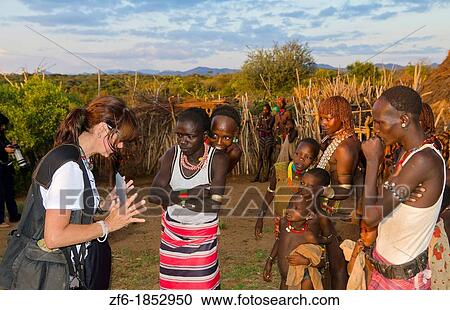 Turmi Ethiopia Africa Lower Omo Valley village with tourist showiing Digital tablet movie to Bena Tribe locals in village 24 View Large Photo Image Stock Image - Turmi Ethiopia Africa Lower Omo Valley village with tourist showiing Digital tablet movie to Bena Tribe locals in village 24. Fotosearch