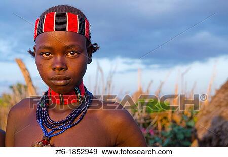 Stock Photo - Turmi Ethiopia Africa Lower Omo Valley village with teenage Bena tribe girl portait at sunset in wood hut village 24. Fotosearch