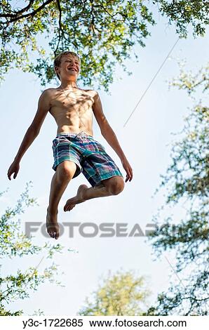 Stock Photography - Twelve years old boy jumping on trampoline. Fotosearch